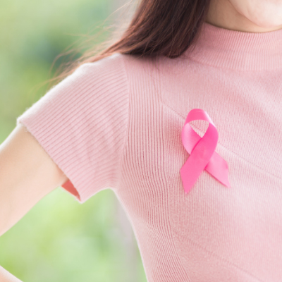 A woman wearing a pink shirt with a pink ribbon symbolizing breast cancer awareness