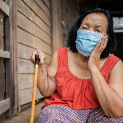 An old woman wearing surgical mask anxious about getting infected.