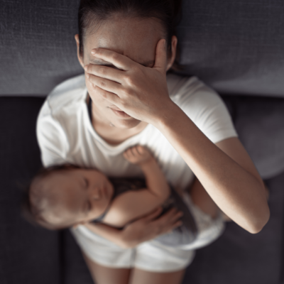 A mother cradling her newborn close, shielding her face with tender affection, captured from above.