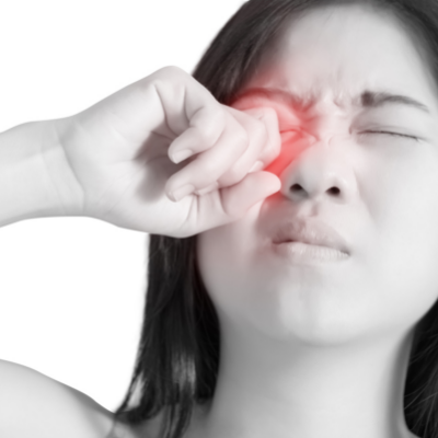 A black and white image of a young woman rubbing her right eye with one hand. The area around her eye is highlighted with a red glow.