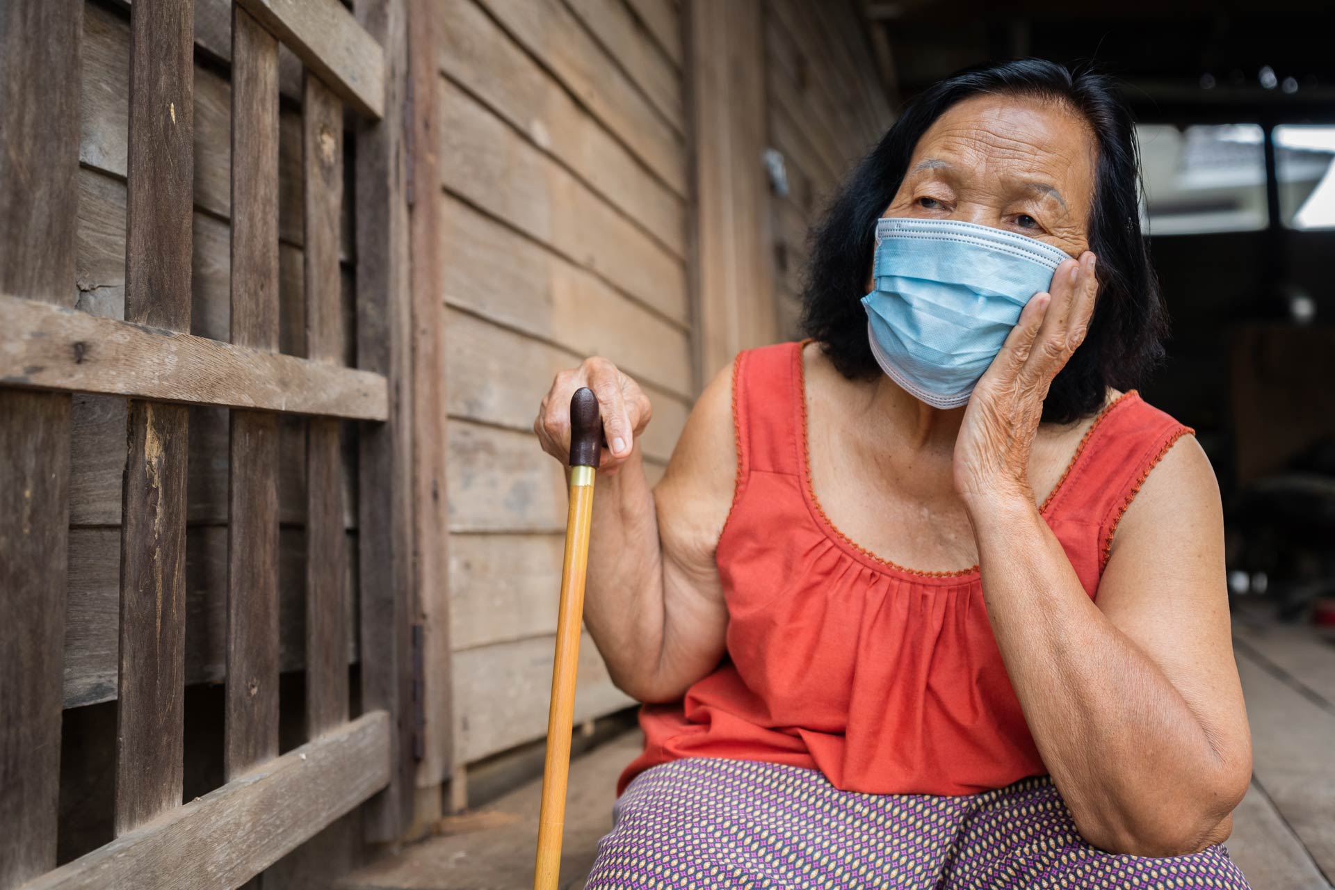 An old woman wearing surgical mask anxious about getting infected.